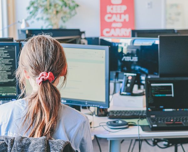 A software engineer focused at a multi-monitor workstation reviewing code